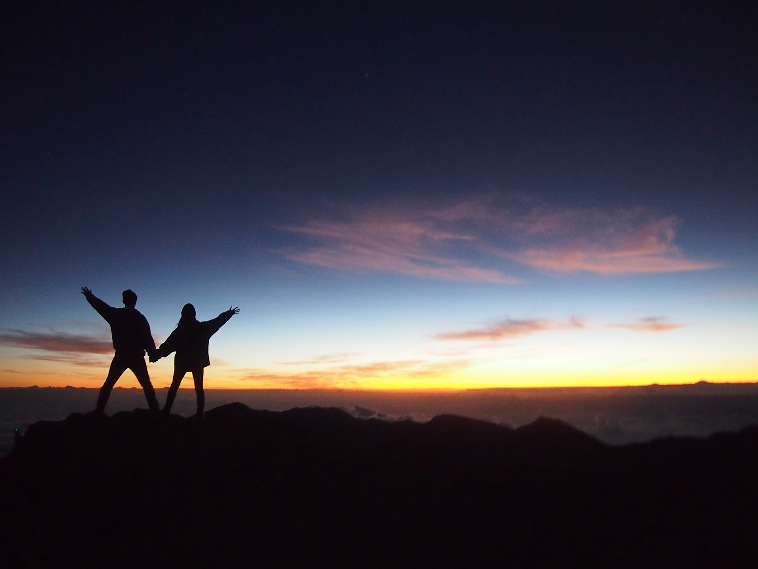 夕日を背に手をつないだ二人のシルエット