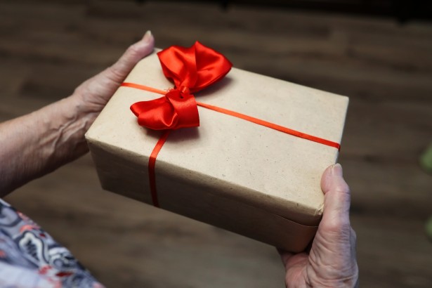 gift box with red bow in grandmother hands macro