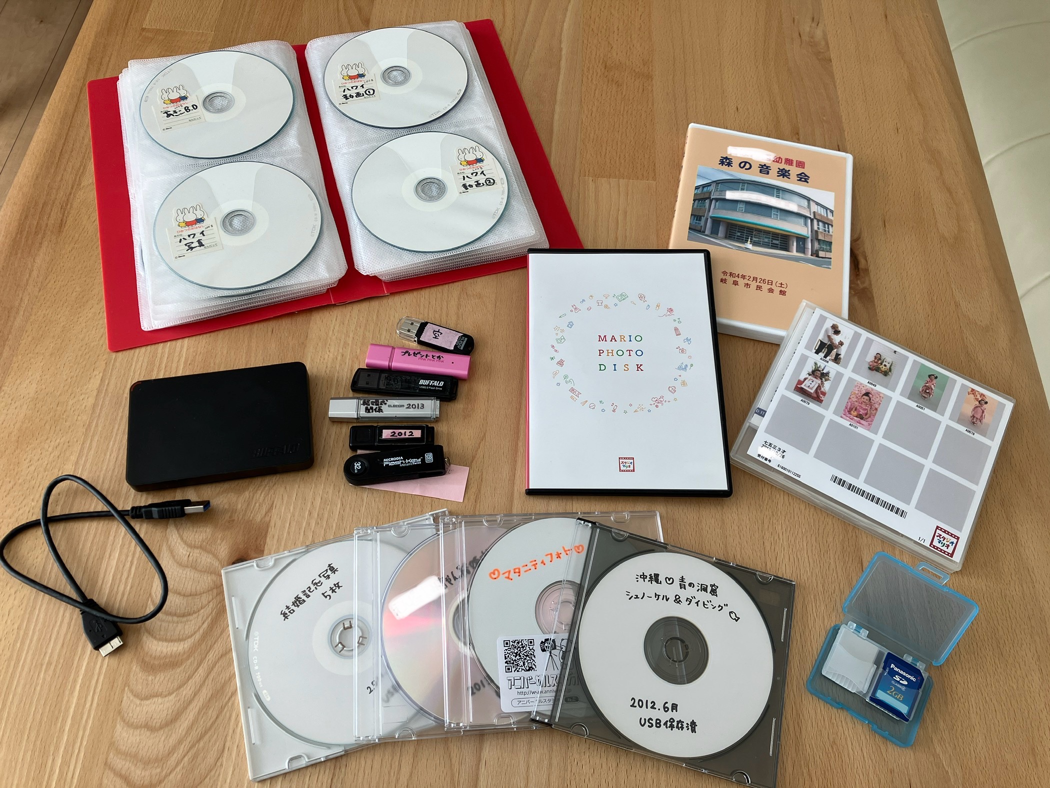 たくさんの写真や動画の詰まったDVD、USBメモリー、ハードディスク、SDカードたち