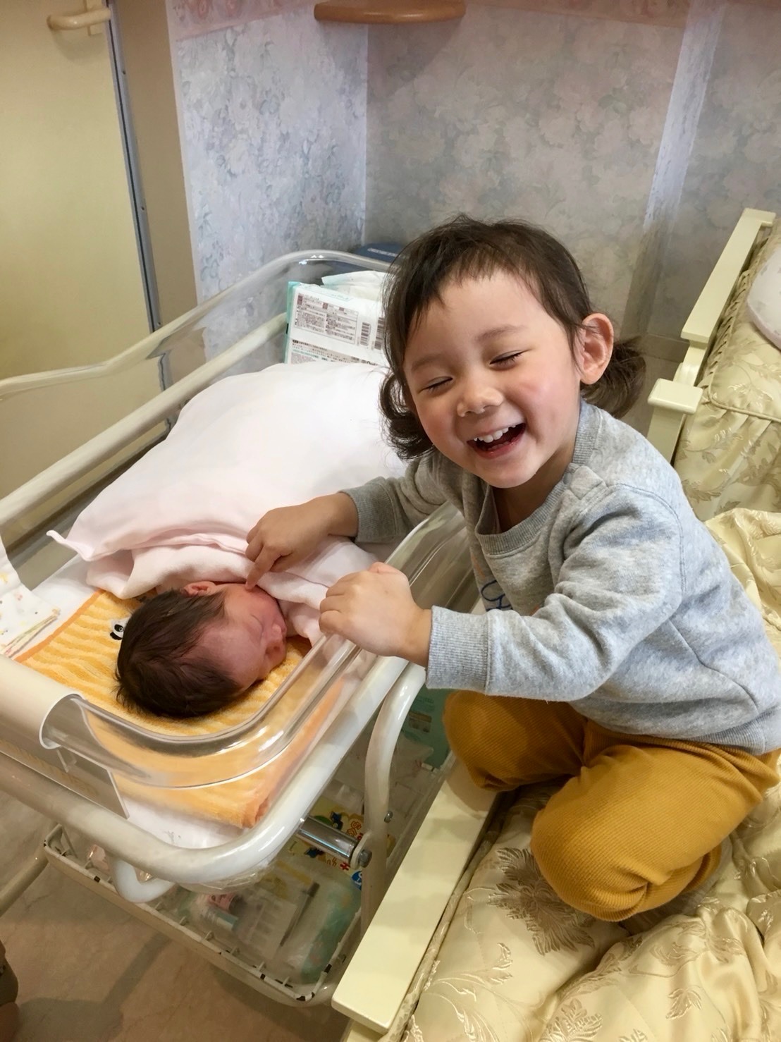 生まれたばかりの妹に寄り添う笑顔のお姉ちゃん