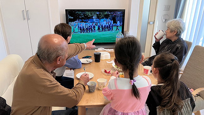 テレビに映し出される写真を見ながら思い出話に花を咲かせる祖父母と孫たち